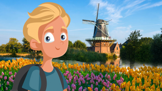 Young boy stands in a field of tulips with a wood windmill in the background