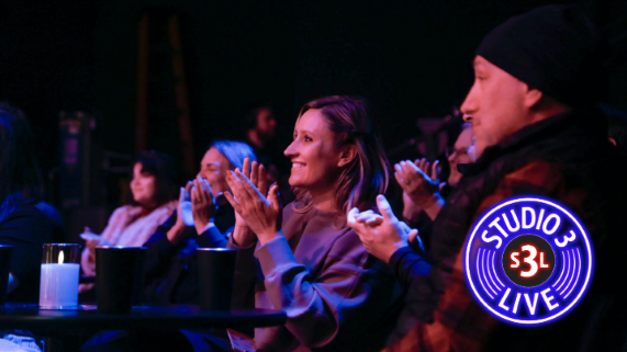 A few people clapping and smiling while watching a musical performance
