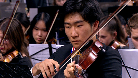 A violinist plays with his orchestra.