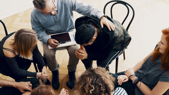 Friends gather around and support a man who is struggling with mental health.
