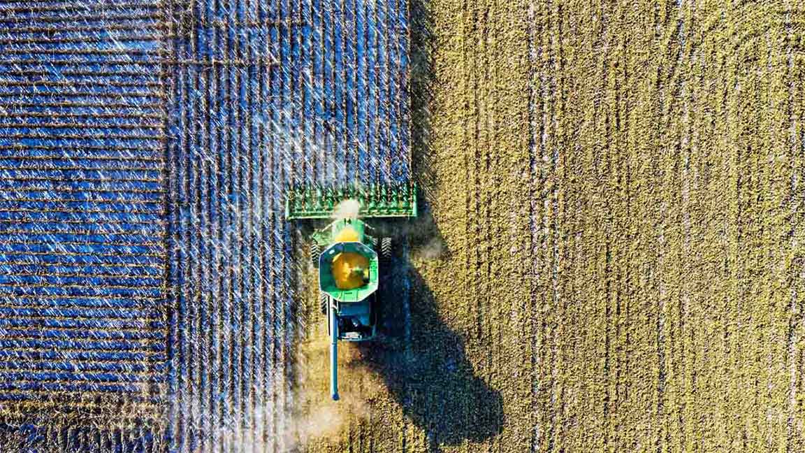 A bird's eye view of a combine harvesting a field.