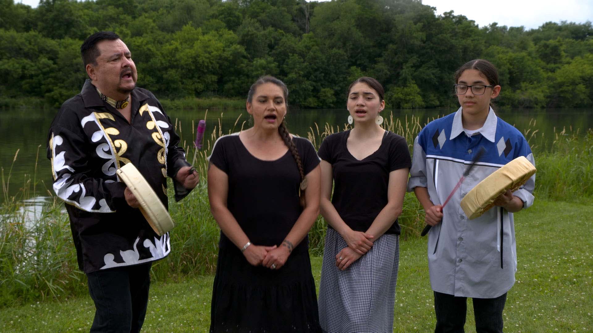 Four Meskwaki Tribe family members singing traditional songs together.