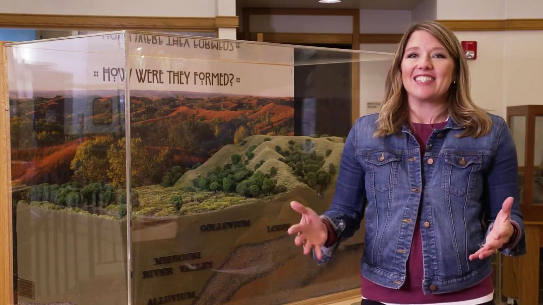 Abby Brown gesturing in front of a model of the Loess Hills.