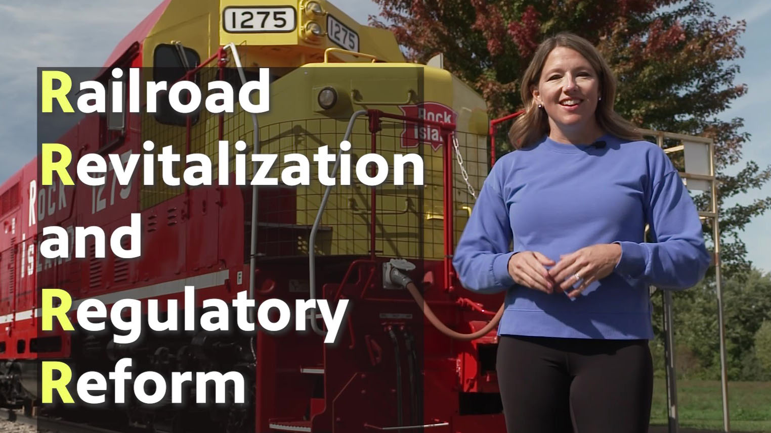 Abby Brown in front of a train locomotive with these words on the screen: Railroad Revitalization and Regulatory Reform.
