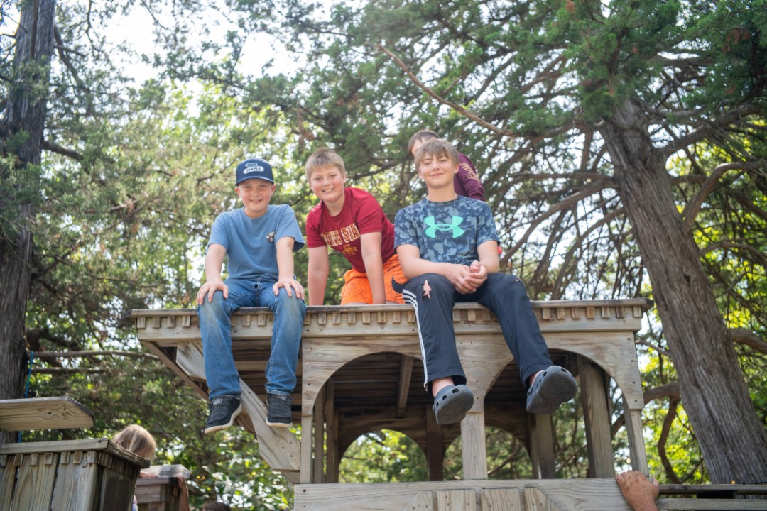 four boys sitting and smiling at the Fair's Fun Forest