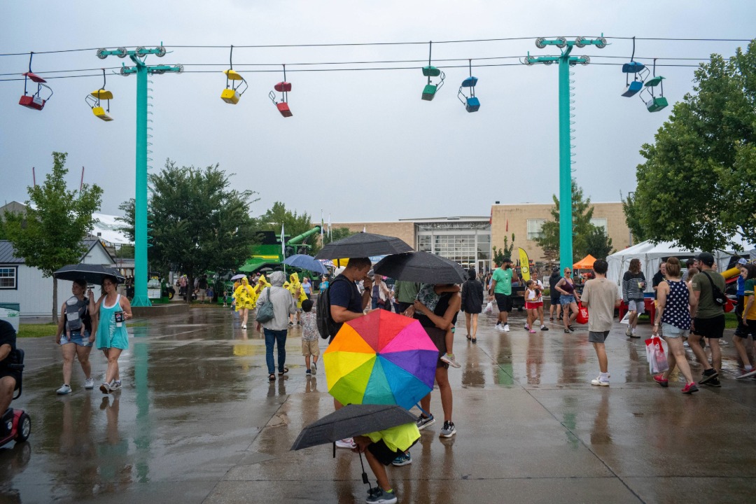 Fairgoers gathered under umbrellas on a rainy day