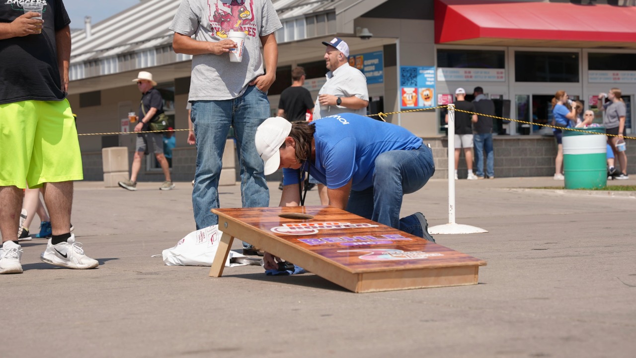 Iowa PBS producer crouching to put camera into cornhole board