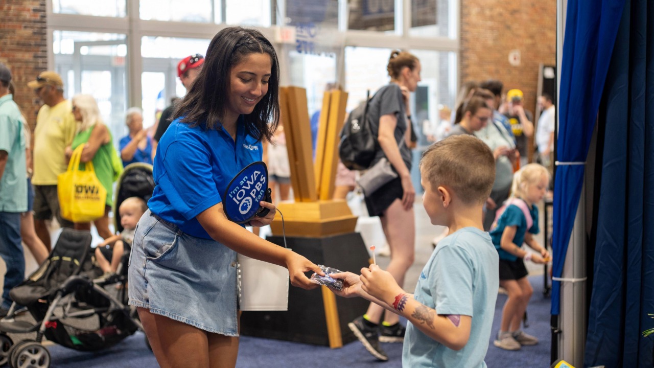 Iowa PBS staff member handing out a fan 