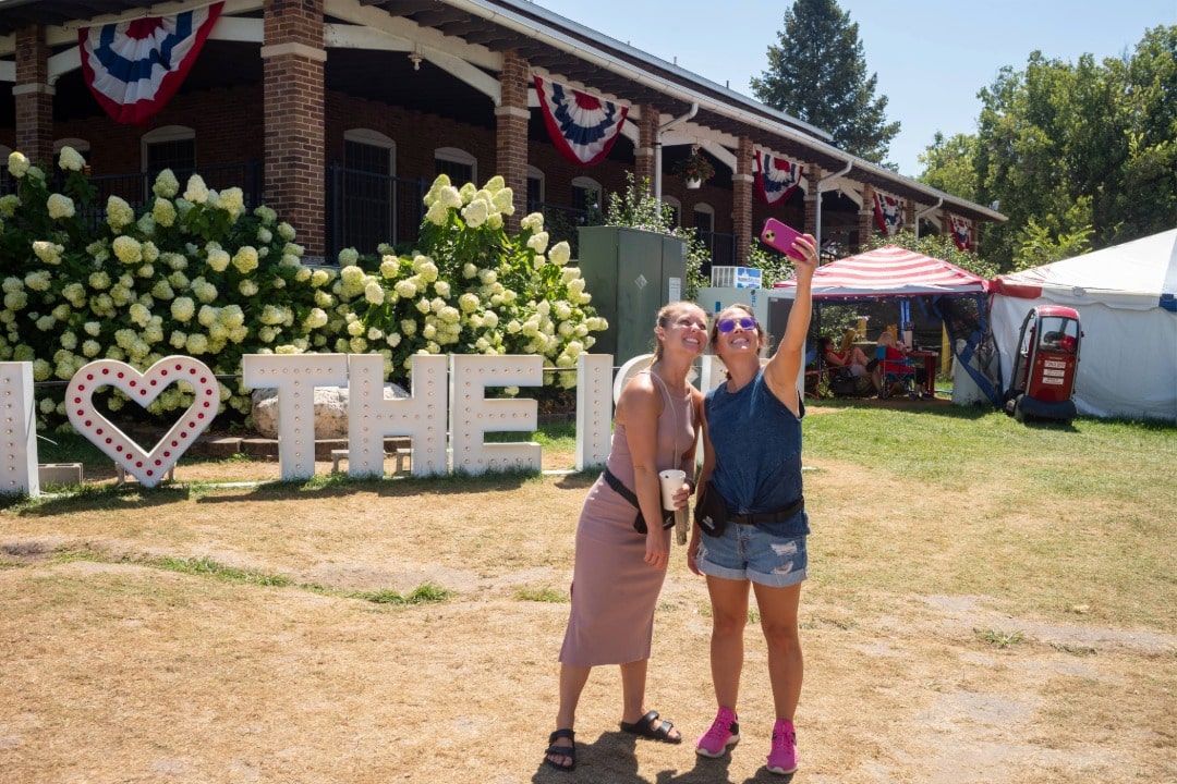 Two people taking photo in front of I [heart] the ISF sign