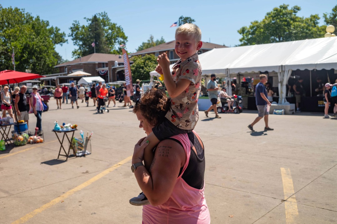 Child riding on an adult's shoulders at the Iowa State Fair
