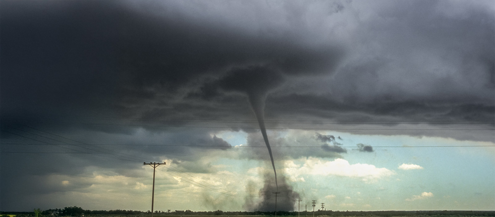 A tornado rolling across a farm field. 