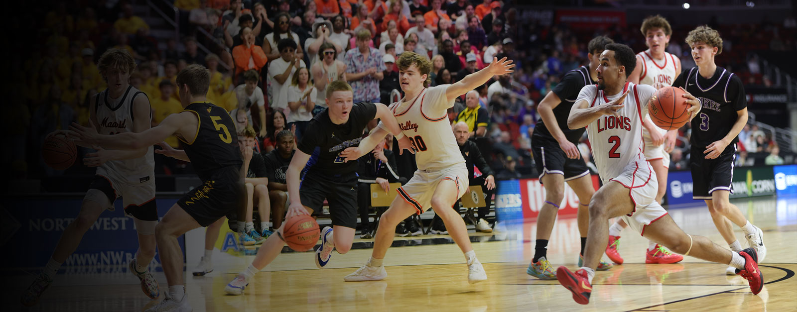 High school boys playing basketball in an area with fans in the bleachers