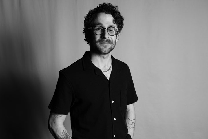 A professional headshot of Mickey Davis, a man with dark curly hair and dark rimmed glasses.