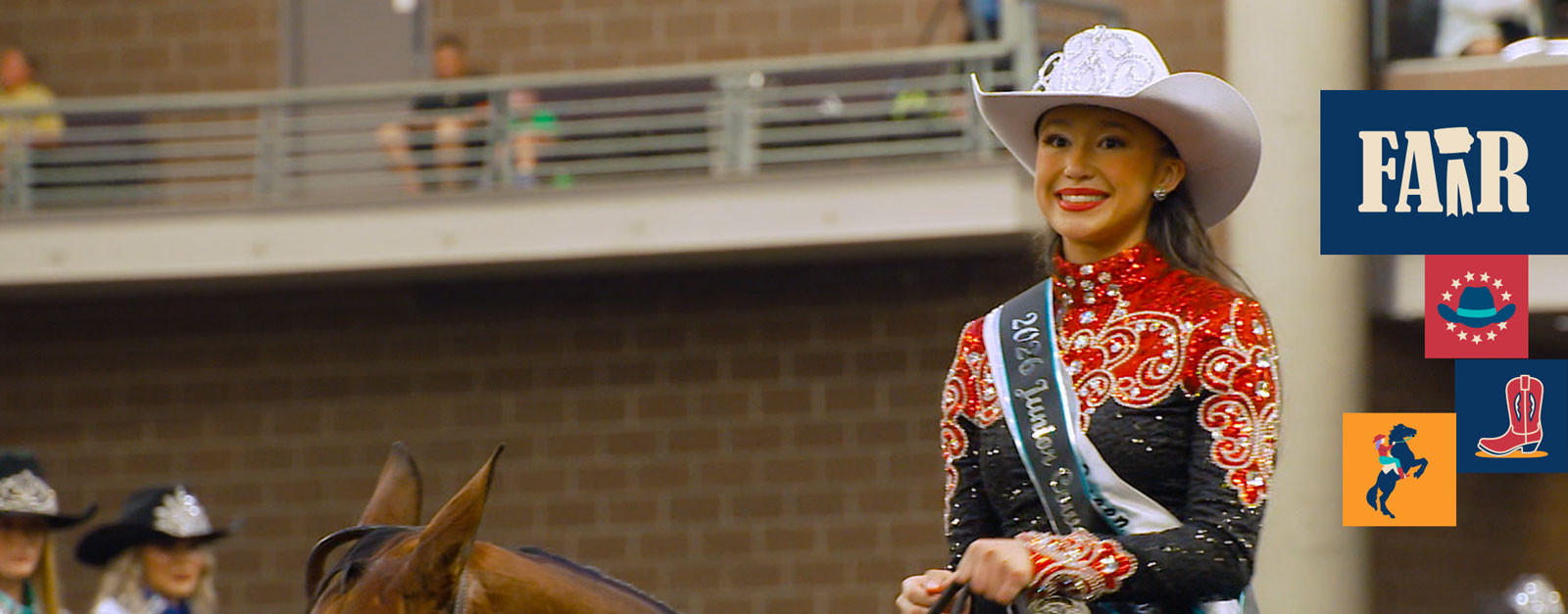 A teenage cowgirl in a sparkling black and red costume and white cowboy hat.