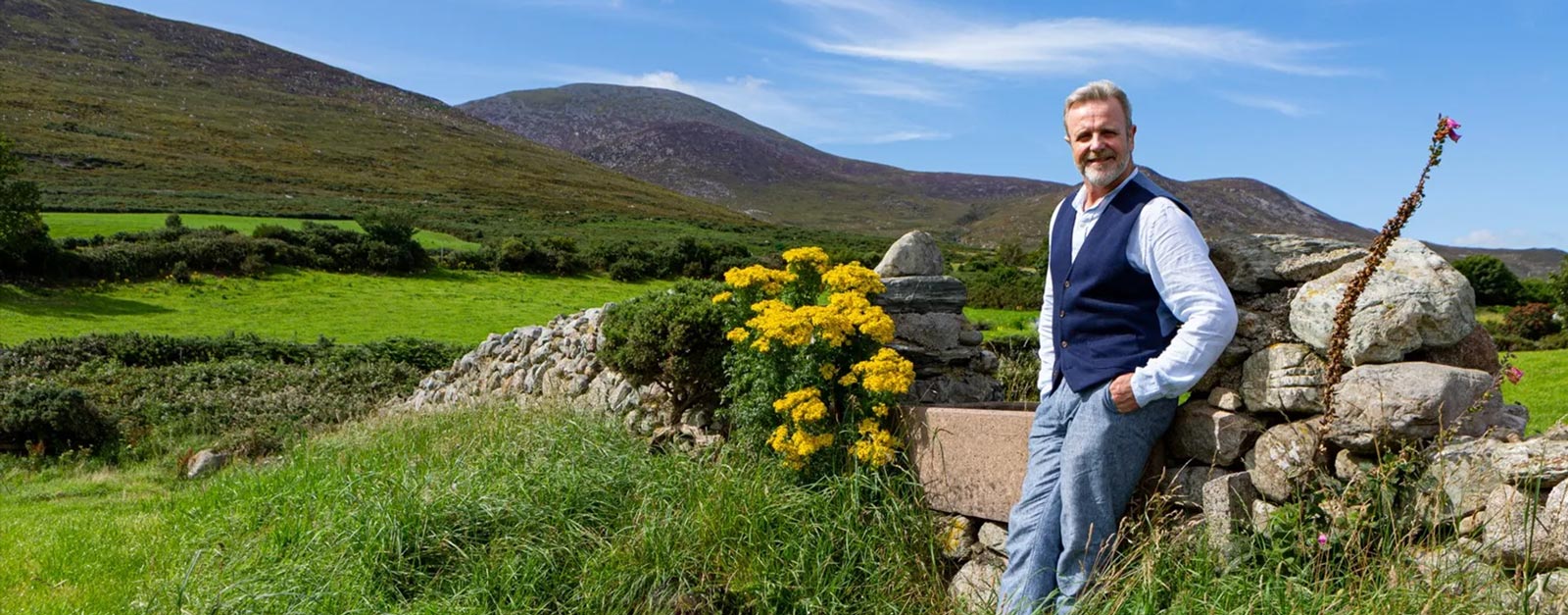 Michael Londra leans against a rock wall in Ireland.
