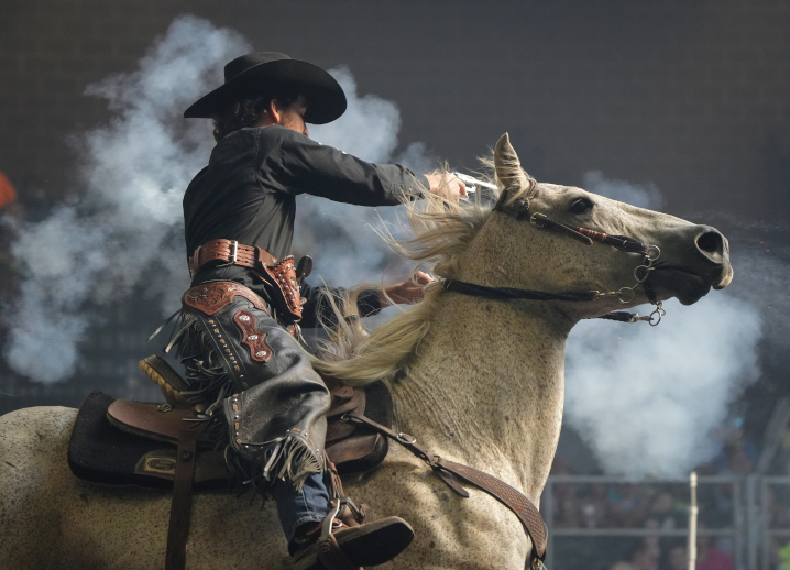 white horse with a rider during cowboy mounted shooting