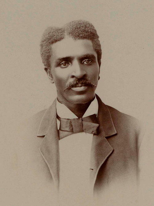 A young black man wearing a white collared shirt, suit jacket and bow tie.
