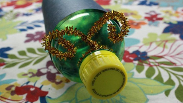 A clear soda bottle with a pipe cleaner wrapped around the neck of the bottle. The pipe cleaner is bent to resemble antennae.