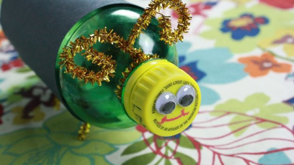 A cap of a clear soda bottle with a face made with googly eyes and a red line for a smile.