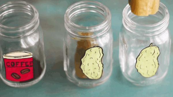 Four clear jars with items in the bottom. The jars have visual and/or text labels. One of the labels says Coffee. One of the images is an image of a potato.