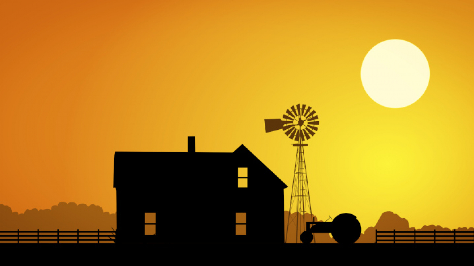The silhouette of a farm house, windmill and tractor against a yellow sky