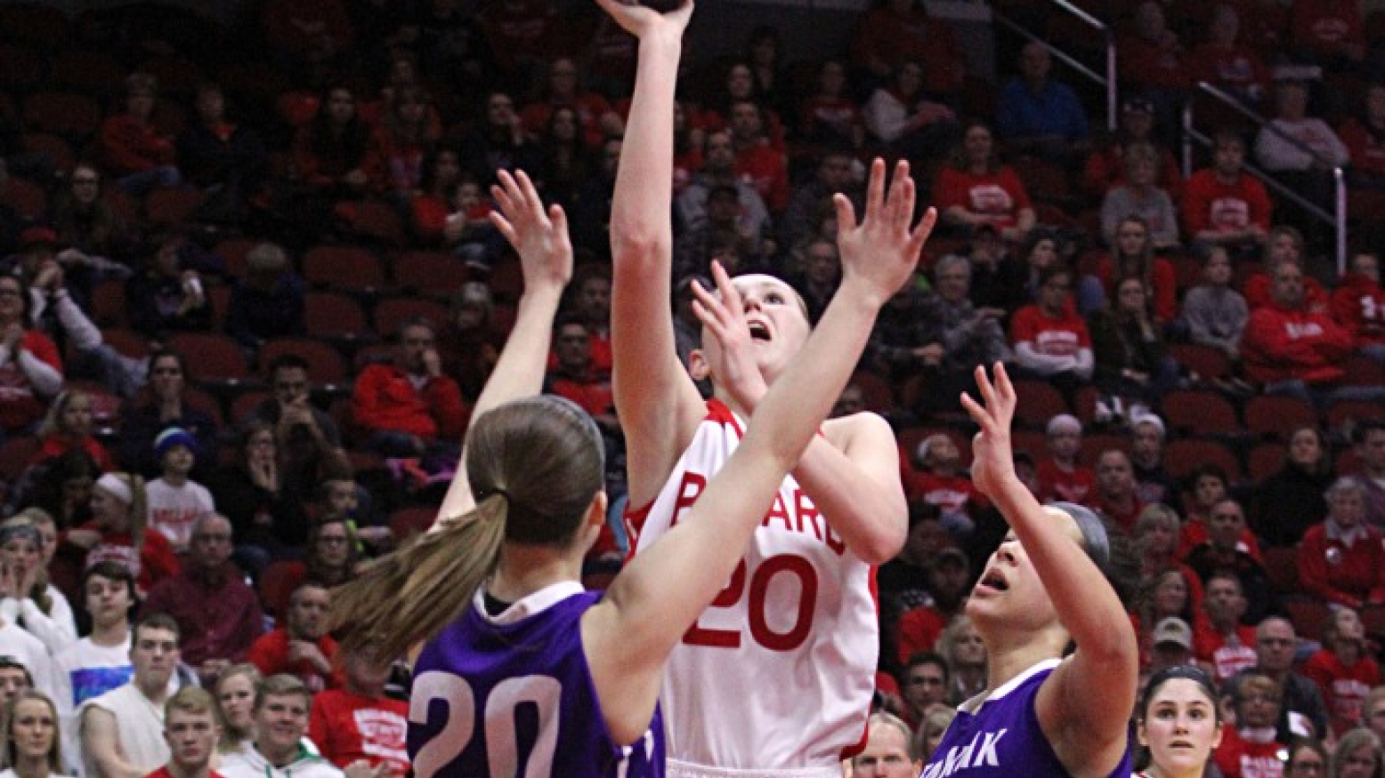 Three high school girls battle over the basketball