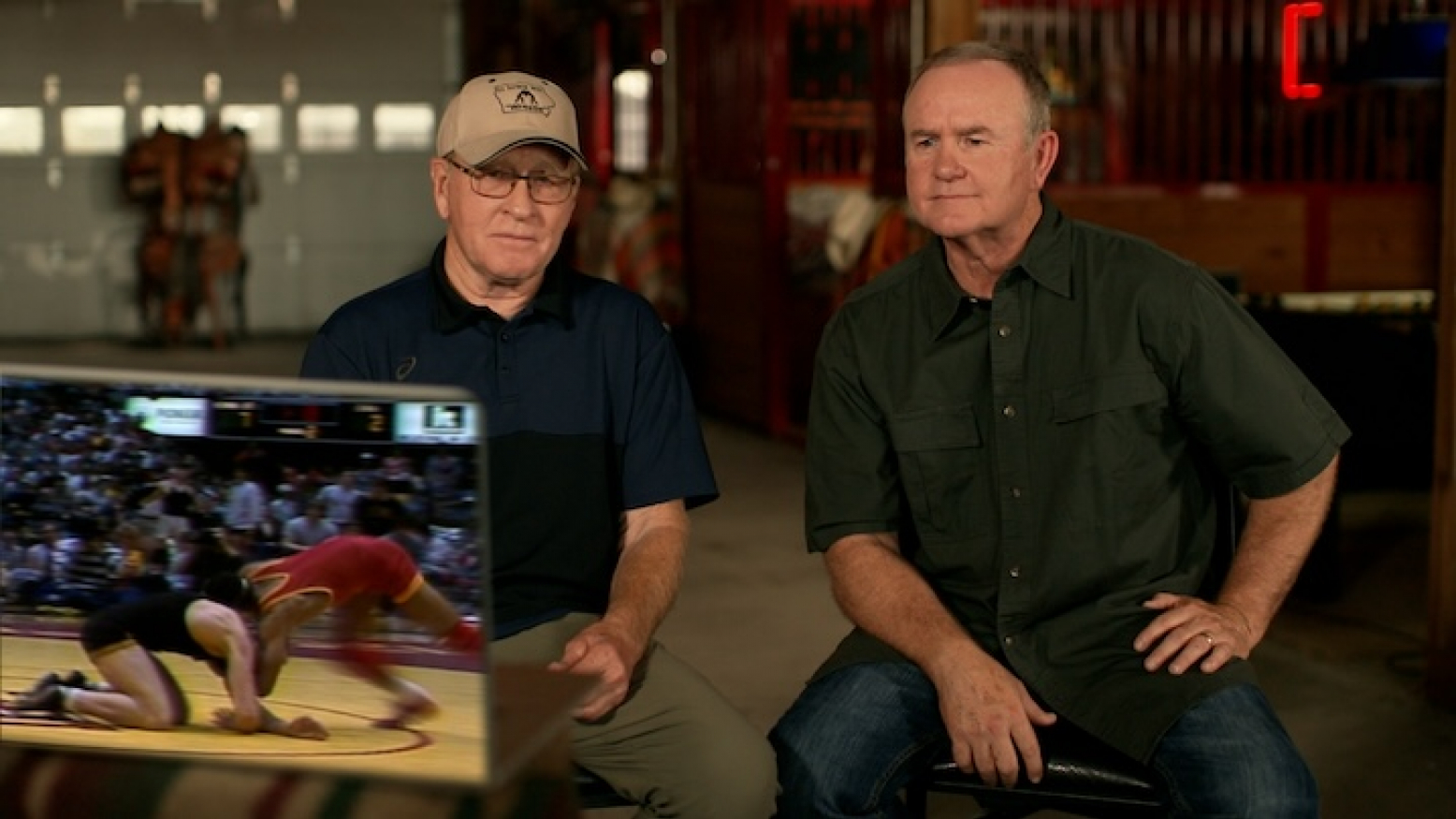 Former wrestling coaches Dan Gable, left, and Jim Gibbons, right, sit and watch footage of a 1986 Iowa v. Iowa State wrestling dual meet. 