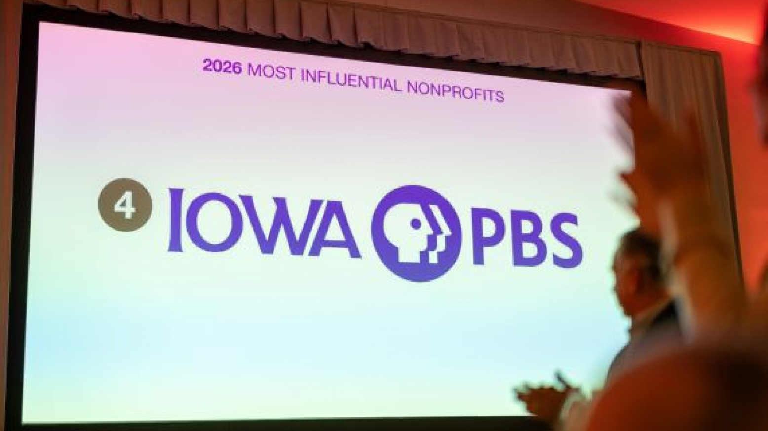 A large screen at an event with the Iowa PBS logo on the screen