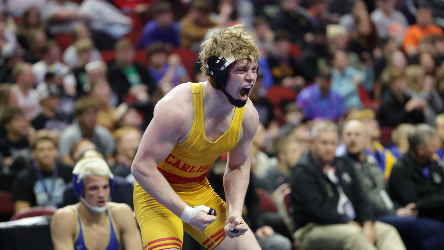 High school male wrestler celebrating win with mouth open and arms in fists