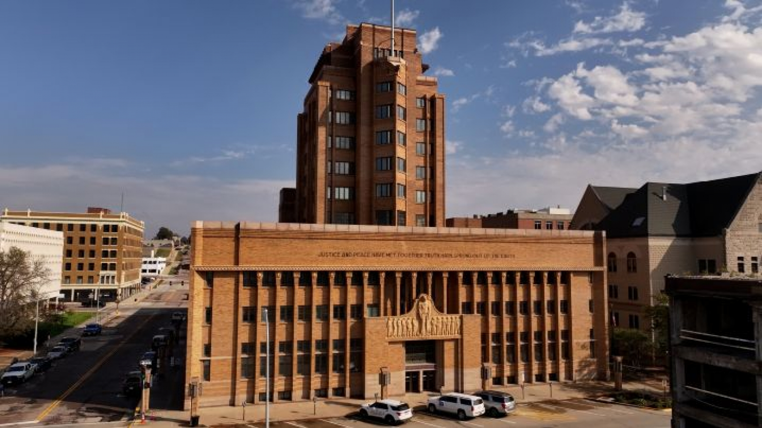 Woodbury County Courthouse in Sioux City, Iowa, a tan-brick neoclassical building with columns and a central sculptural entrance, viewed from above.