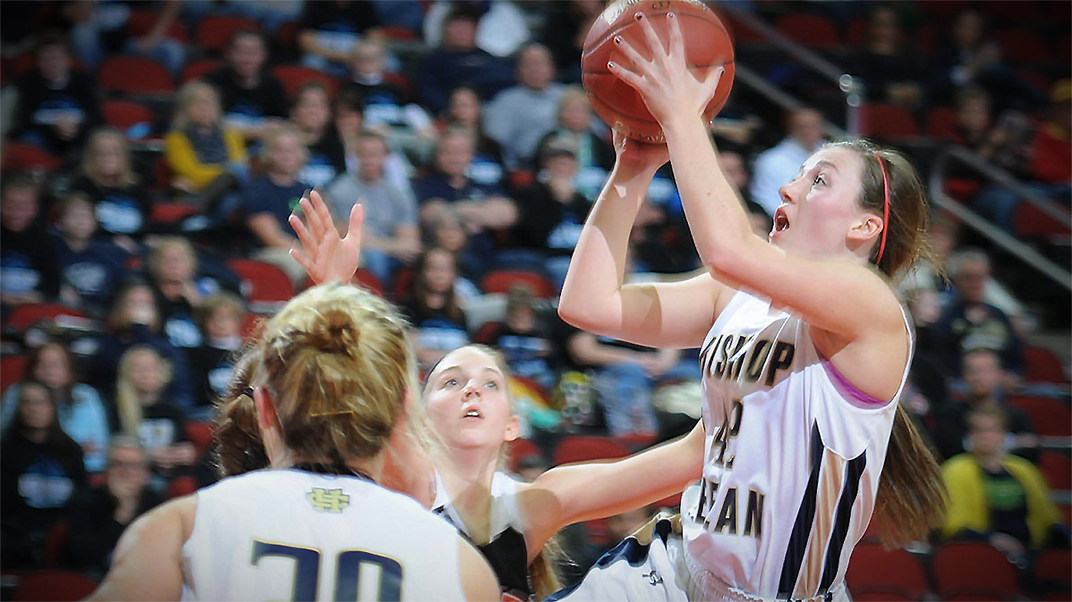 High school girls basketball players -- one taking a shot at the basket.