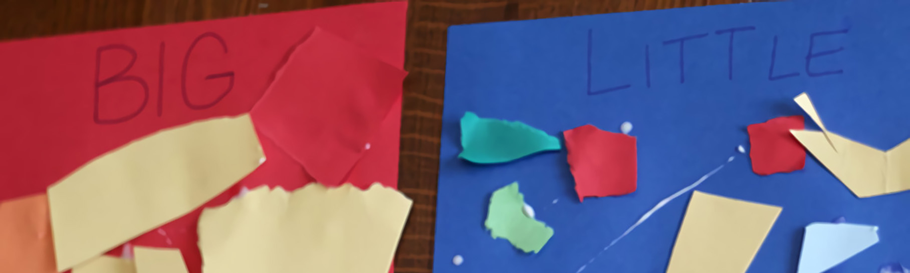 Two pieces of construction paper. One is red and one is blue. At the top of the red paper it says “big.” At the top of the blue paper it says “little.” There are pieces of paper of various sizes on the red and blue paper.