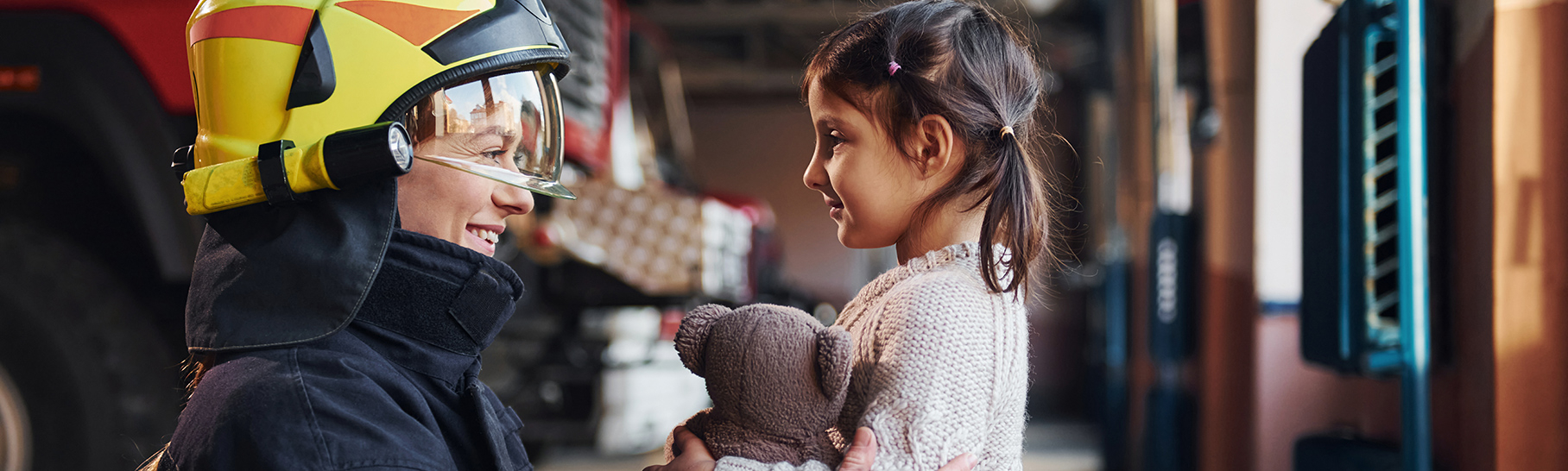 Firefighter with little girl holding a teddy bear.