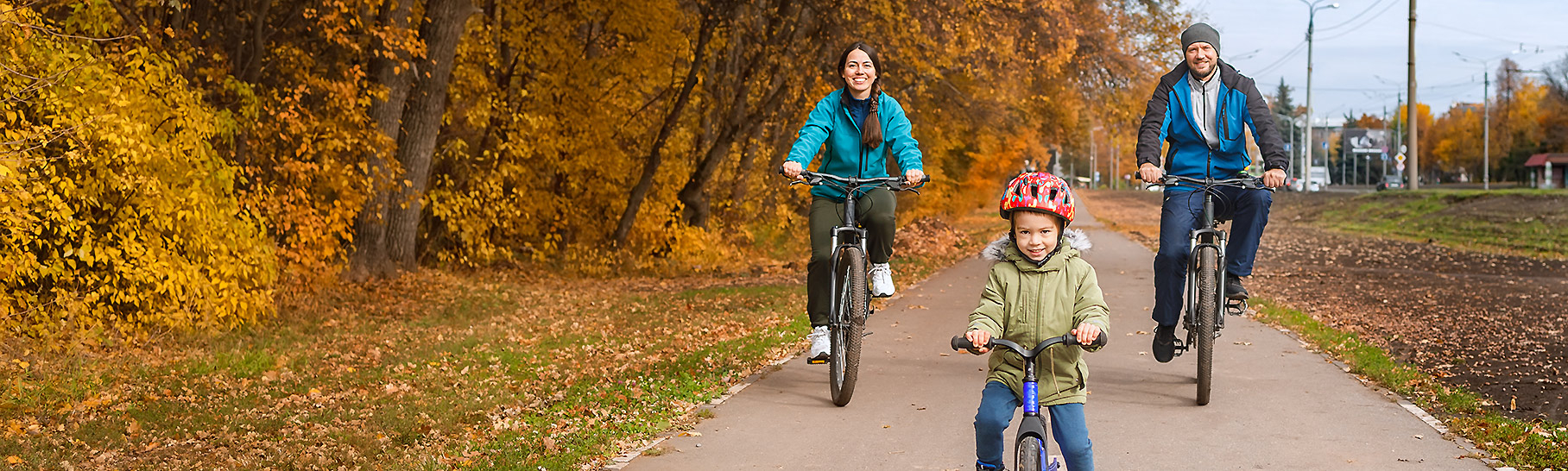 A family of three riding bikes on a cool fall day.
