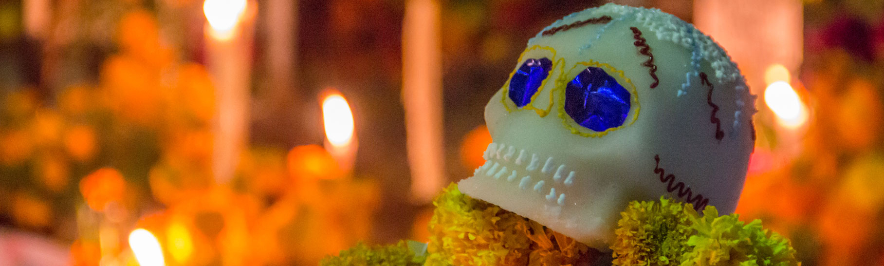Decorative skull placed on an ofrenda with candles lit in the background
