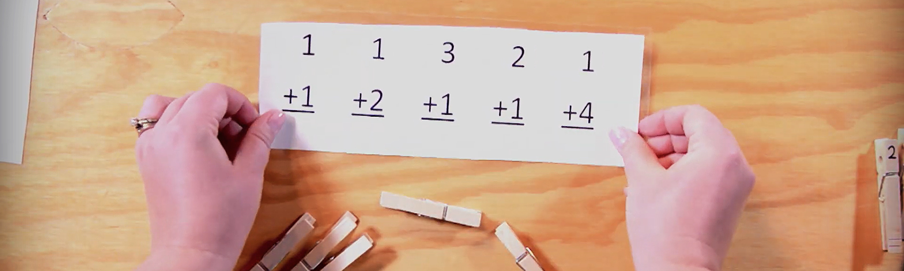 A set of hands holding a math sheet to be used with clothespins.