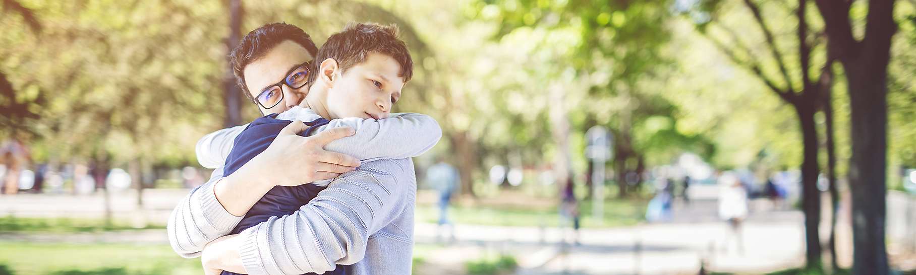 A father and son hugging in a park.