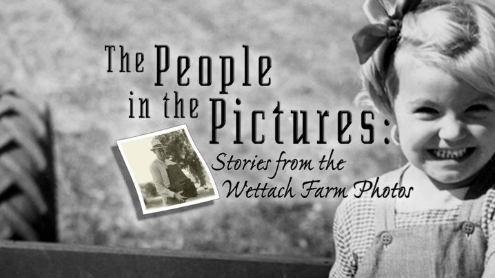 a black and white image of a small child smiling at the camera sitting on a tractor.