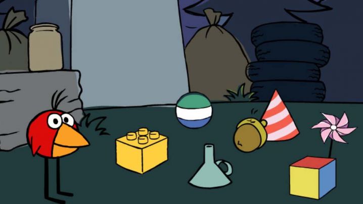 A red bird observes objects on the ground including a funnel, building block, ball, acron, party hat and pinwheel.