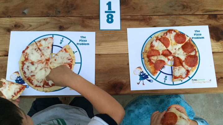 Two children sitting in front of their personal pizza on the pizza placemat with the one eighth fraction card above their personal pizza.