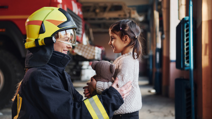 Firefighter with little girl holding a teddy bear.