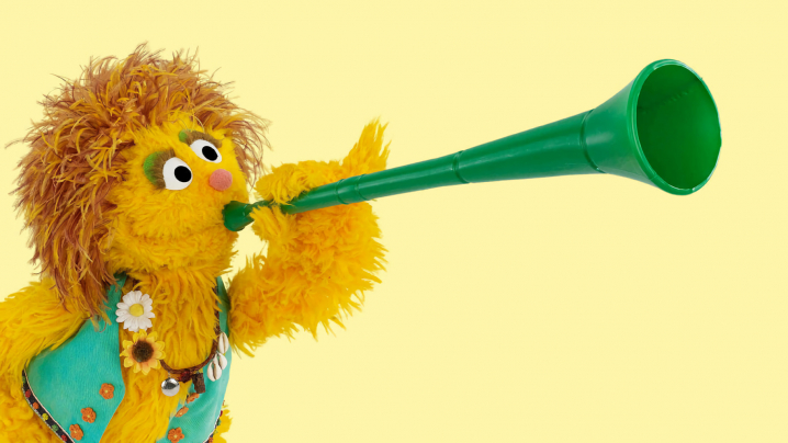 A sesame street character blowing a horn.