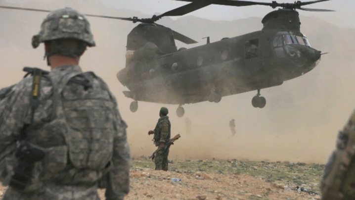 American soldiers standing on the ground as a helicopter comes in to land