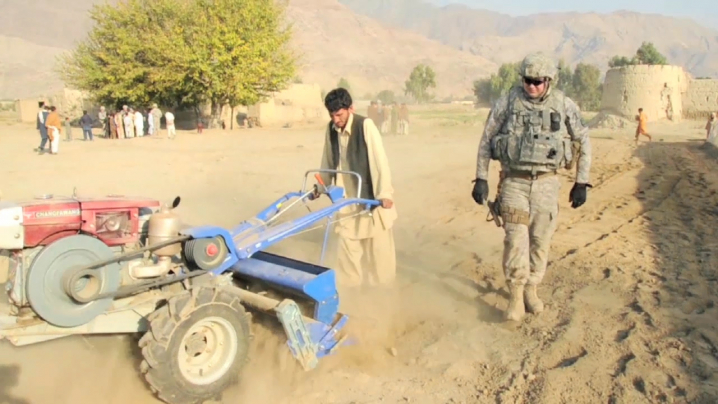 Iowa National Guard Soldier working along side an afghan farmer to prepare the soil for crops.