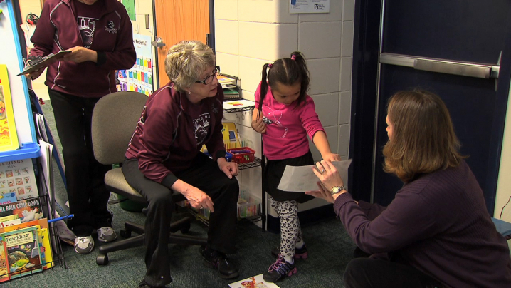 teacher and para educator working with a student to identify parts of a fictional story.