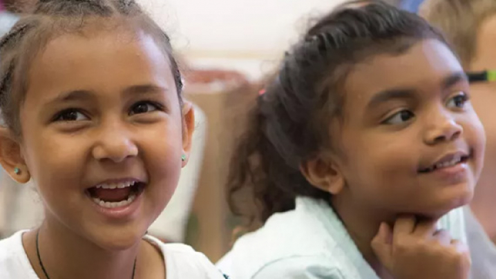 two young girls smiling and laughing as they watch a live show