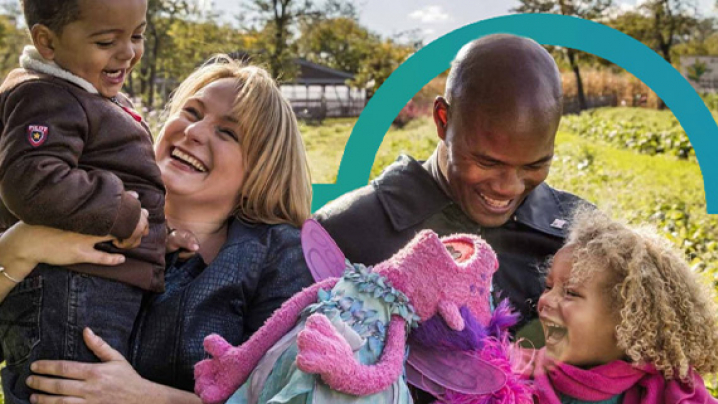 A young family laughing with a sesame street character