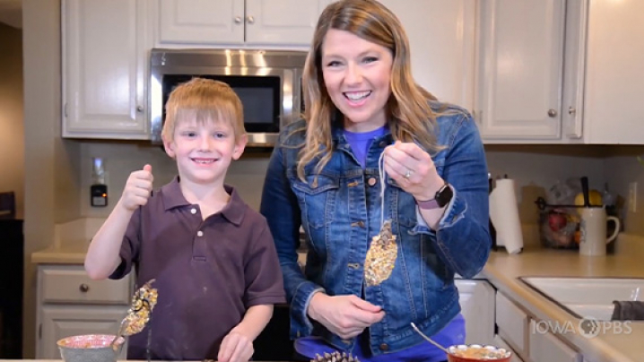 Abby and her friend hold up homemade bird feeders.