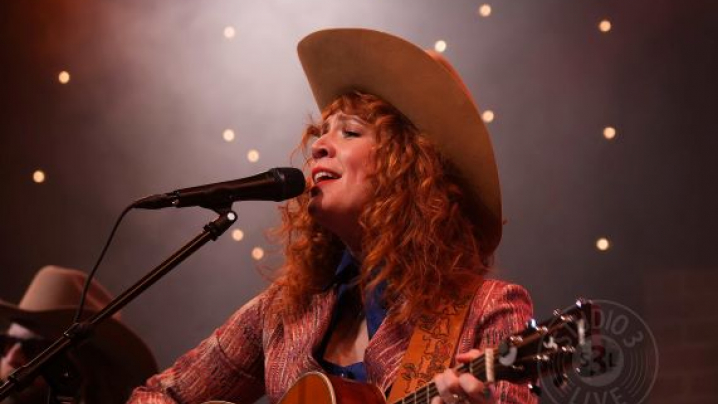 A woman in a cowboy hat singing into a microphone