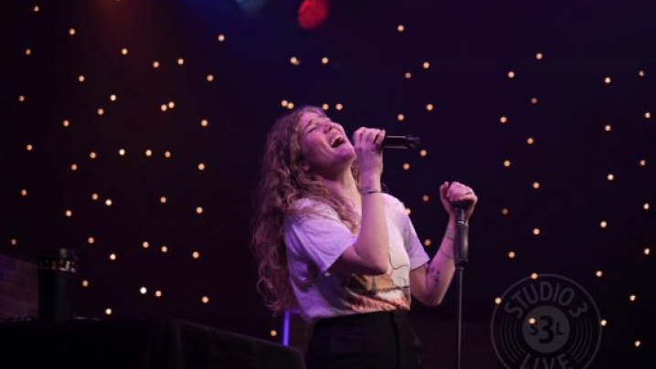 A woman with her head thrown back singing into a microphone